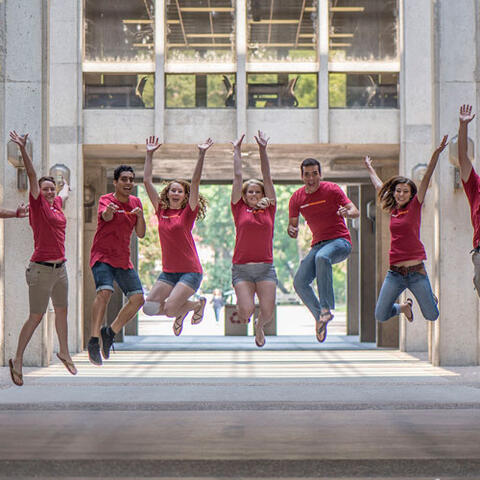 Students in a library hall jumping together in celebration